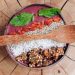 Healthy acai bowl with granola, mint leaves, and berries served on rustic wood.